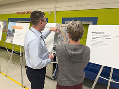 Public meeting with two adults looking a project board