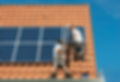 Workman Installing solar Panels on Red Tiled Roof in Summer