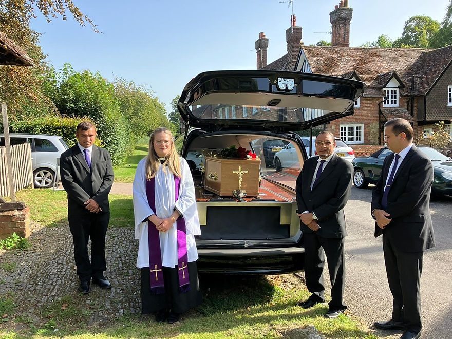 Hearse with oak coffin and red floral tribute English village UK
