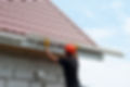 Workman repairing guttering on side of a house