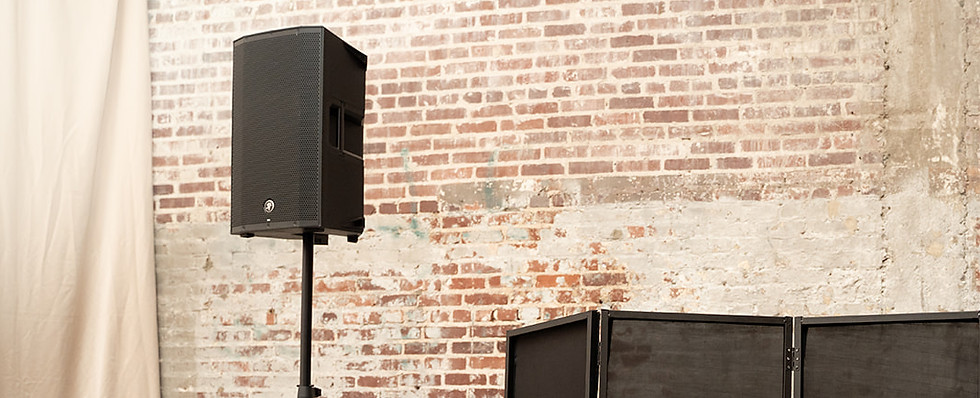 Close-up of a professional speaker setup and DJ booth in a venue with exposed brick walls.