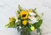Golden yellow sunflower arrangement with white hydrangea, ranunculus, tulips, chamomile daisies, and lush greenery in an airy garden-style floral design by Laurel & Leaf in Franklin, Tennessee.