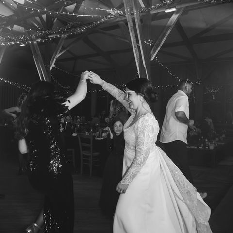 La mariée dansant avec une invitée sous les guirlandes lumineuses du Domaine de l’Oiselière à Chauché en Vendée, dans une ambiance chaleureuse animée par un DJ professionnel.