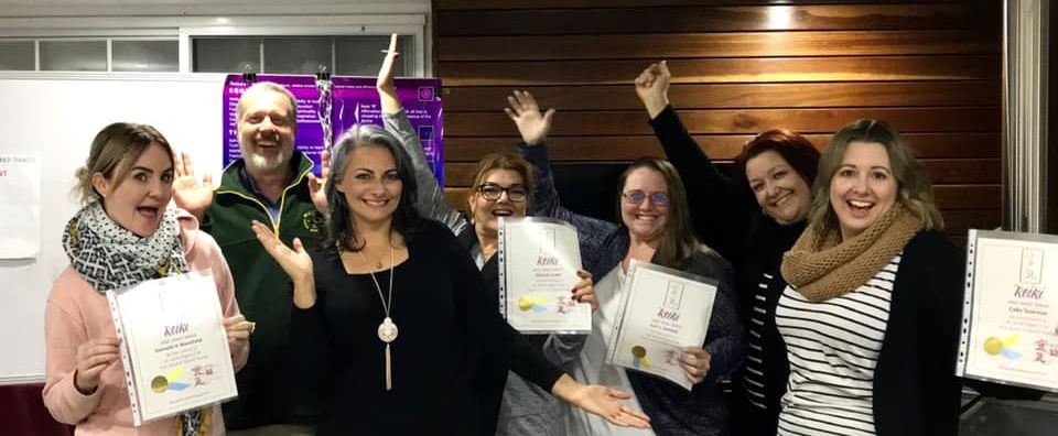 Proud Reiki training graduates displaying their achievement certificates standing with a Reiki Master Joanne Antoun
