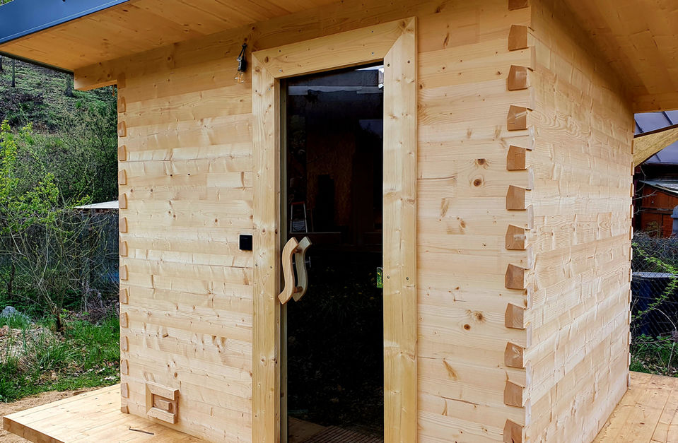 Elegantní venkovní finská sauna v zelené zahradě s dřevěným obložením.