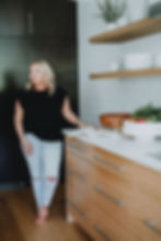 Designer standing in kitchen with cook book open