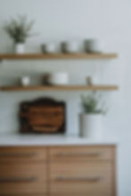 Natural wooden shelves with white ceramic pots and herbs in kitchen