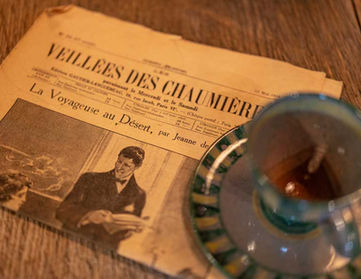 Foto einer Tasse Tee und einer alten Zeitung auf einem Tisch.