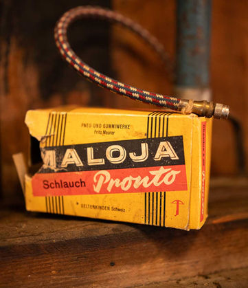 Gelbe Vintage-Schlauchverpackung «Maloja Pronto» mit angeschlossenem Schlauch in Nahaufnahme.