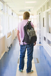 rear-view-of-male-college-student-standing-in-university-corridor-SBI-301057454.jpg