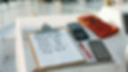 Clipboard with yearly hours and average, red pen, calculator, and red gloves on white surface. Smartphone shows contact screen. Outdoor setting.
