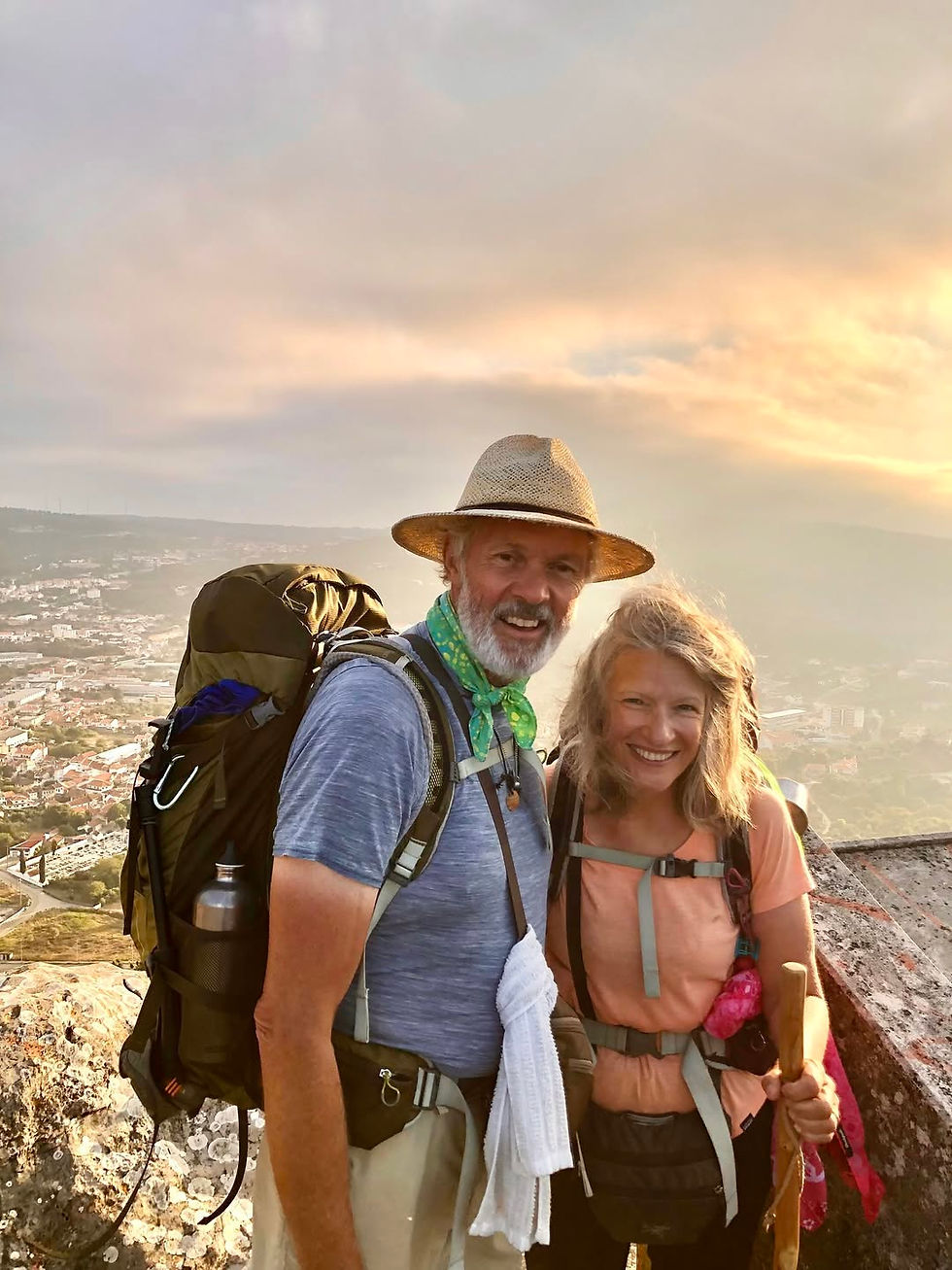Kate and Robert walking the Camino de Santiago together, wearing backpacks in the evening light.