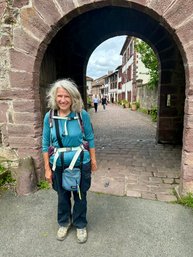 Kate Forrester, a pilgrim and writer, standing beneath the Porte Saint-Jacques in Saint-Jean-Pied-de-Port.