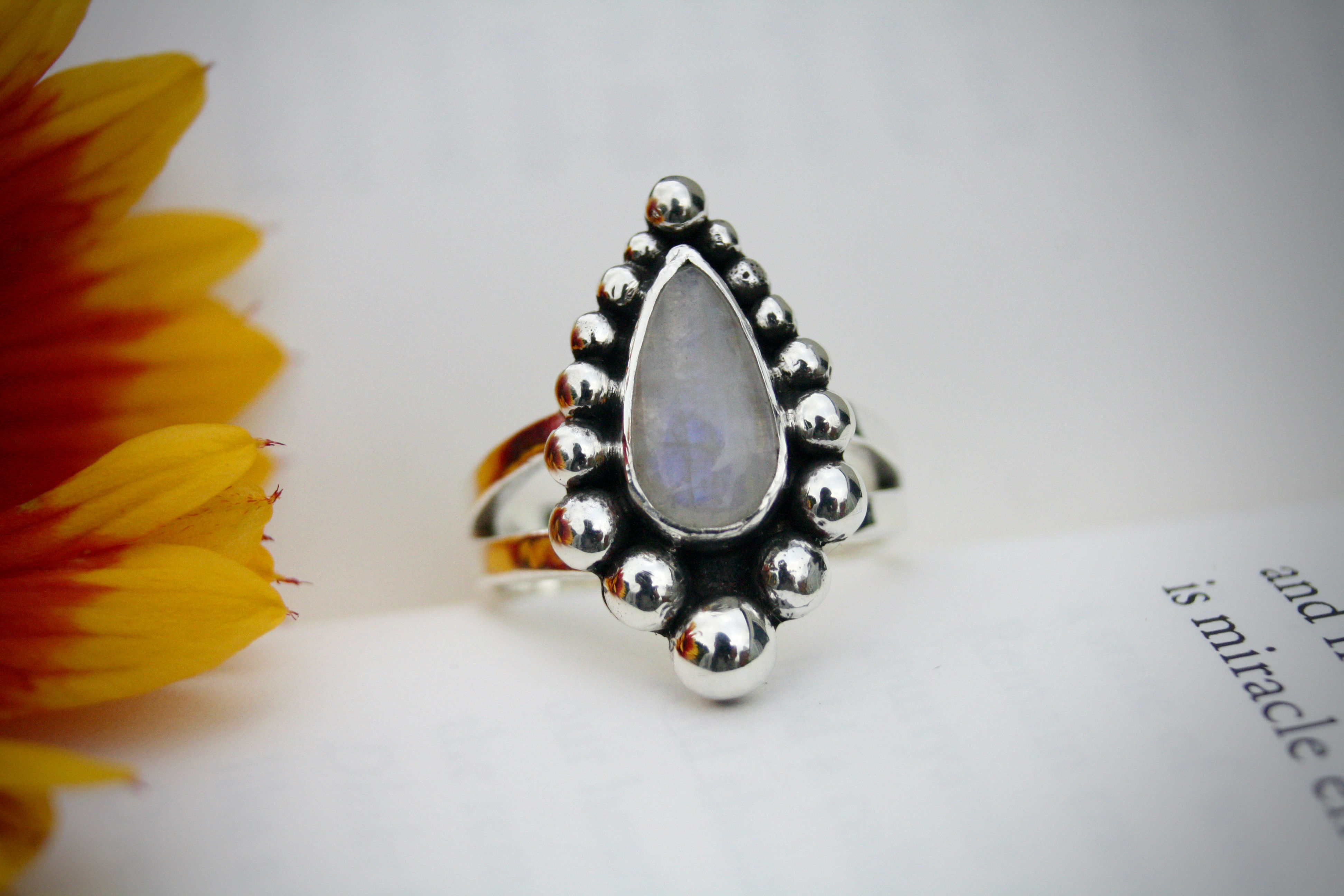 Teardrop moonstone ring with multi size ball boulder border. Split band. Made with eco sterling silver.