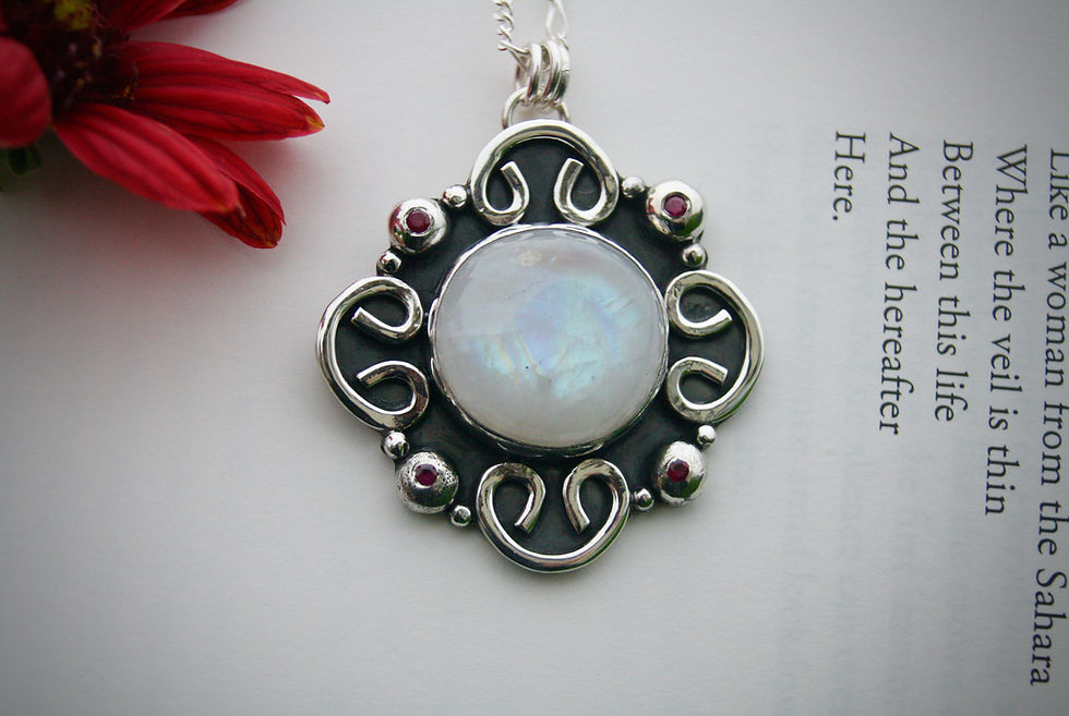 Thumbnail: The unified self. Mandala shaped necklace with shining blue moonstone at centre. Four flush set rubies in each quadrant.