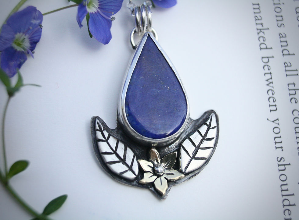 Thumbnail: Nature inspired lapis lazuli necklace. Pear shaped stone with silver leaf border and brass daffodil at the bottom.
