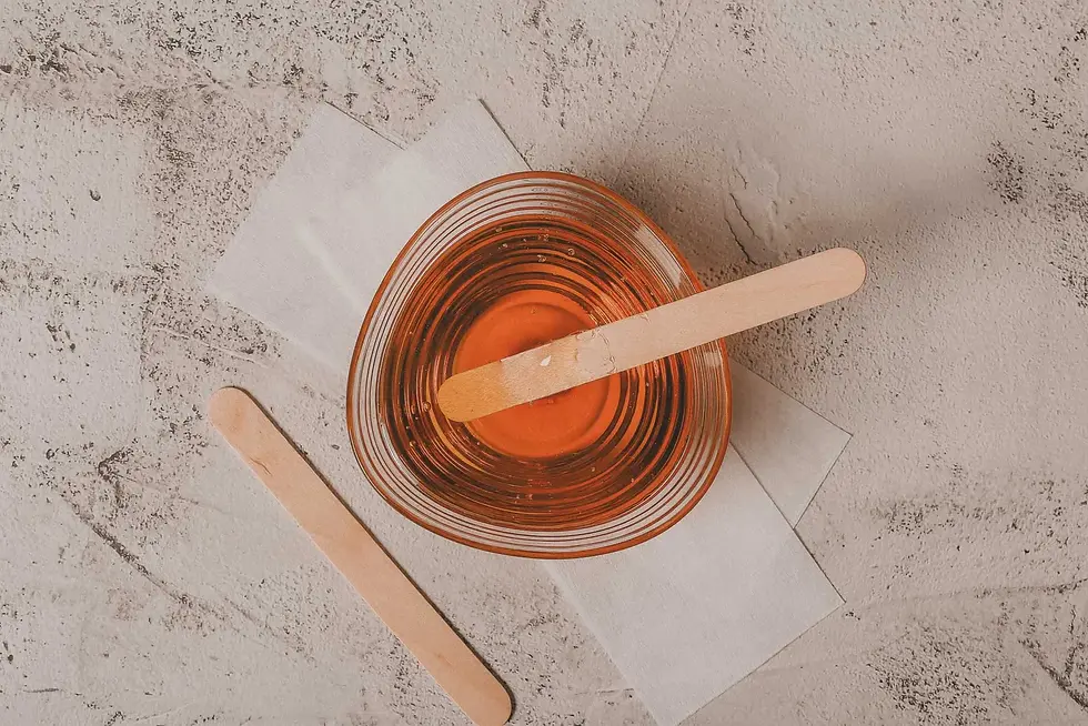 Professional hard wax beads and a wooden spatula used for complete Brazilian waxing services.