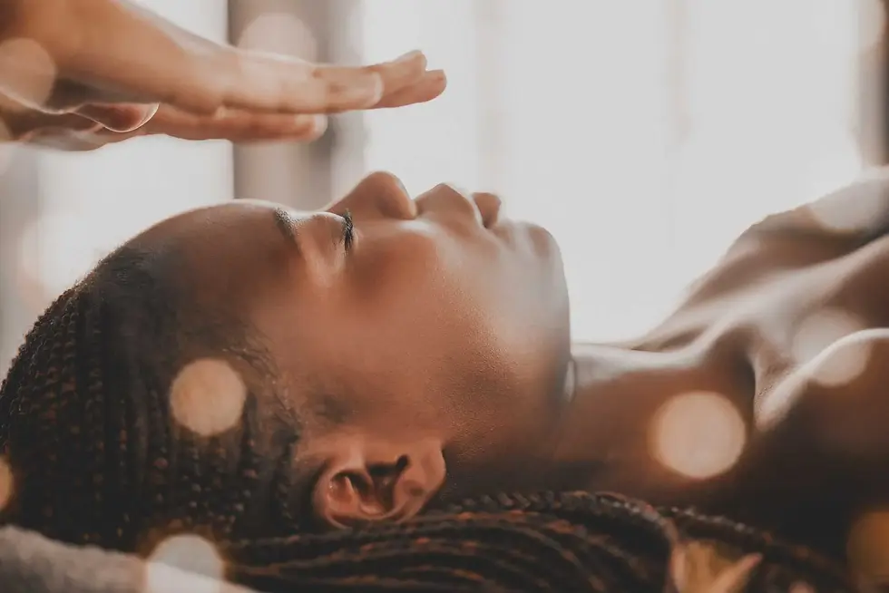 Practitioner performing a Reiki energy healing session with hands hovering gently over the client.