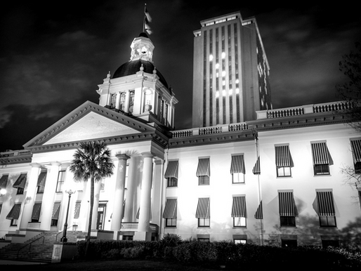 Black and white photo of the Florida Capitol building at night, featuring the historic dome and adjacent legislative offices during the 2025 session.