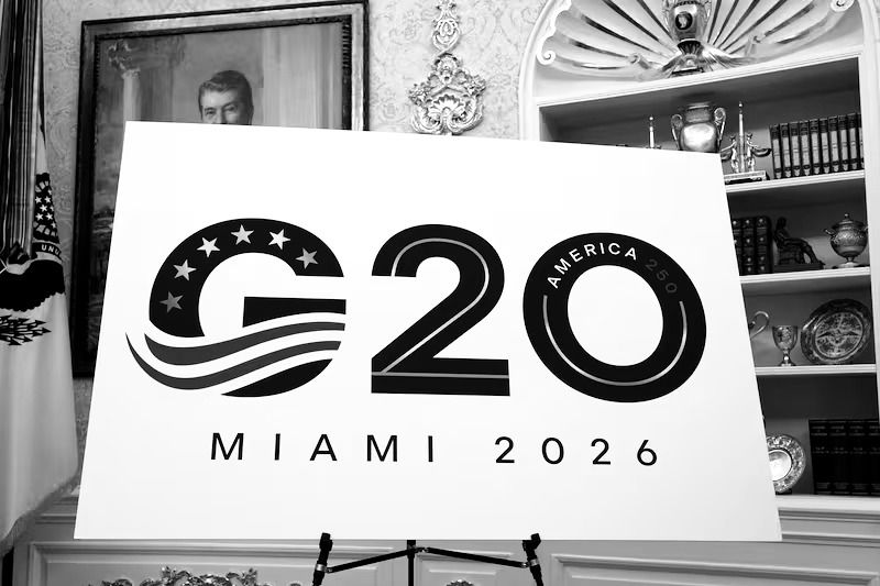 Official logo for the G20 Summit Miami 2026 displayed on a sign at the White House announcement event, featuring bold black text with stars and wave design elements, marking America's 250th anniversary.