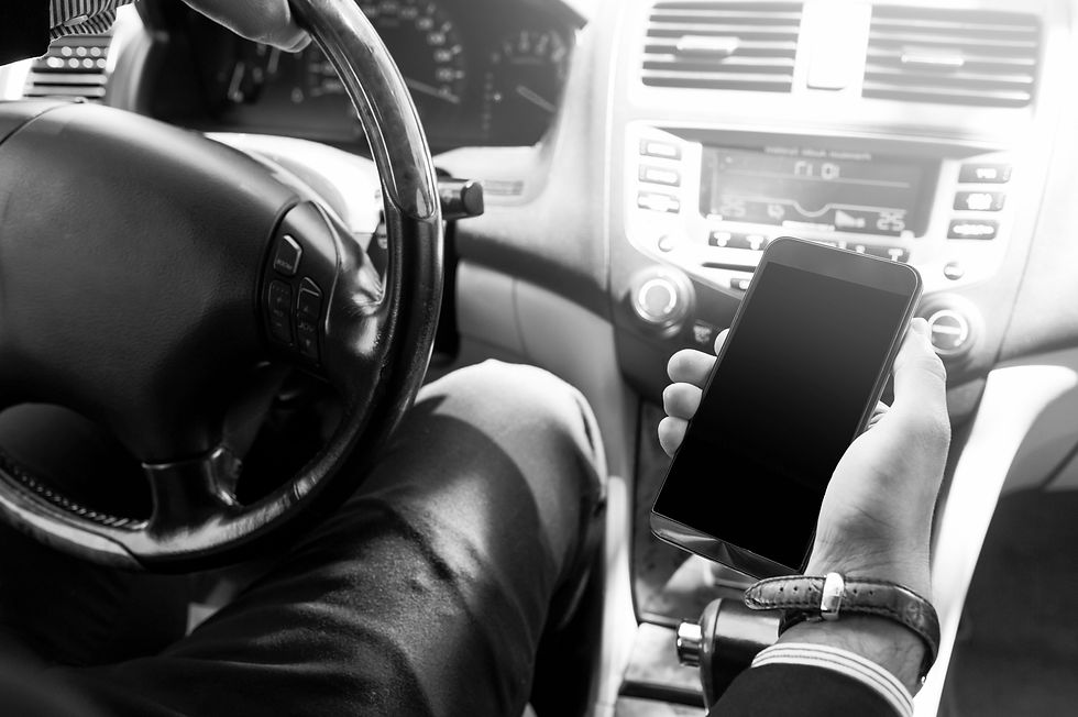 Driver holding a smartphone while operating a vehicle, illustrating digital distraction behind the wheel.