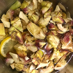 trimmed artichokes in a bowl of lemon water