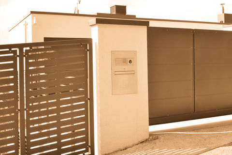 Zaun und Tor mit Briefkasten vor Flachdachgebäude