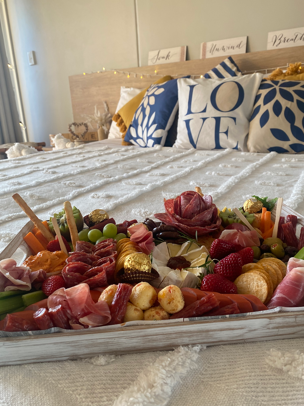 Romantic grazing platter on a bed with LOVE pillows in the background