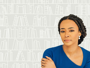 Award winning author, Aaliyah Bilal, wearing a blue top gazes forward. Her image is against a gray backdrop.