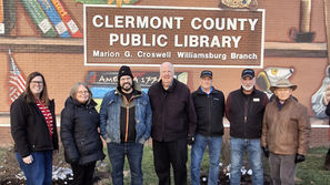 Six people pose outside Clermont County Public Library, Marion G. Croswell Williamsburg Branch, before a mural of books and a butterfly.