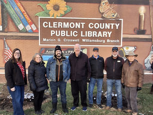 Six people pose outside Clermont County Public Library, Marion G. Croswell Williamsburg Branch, before a mural of books and a butterfly.