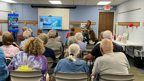 Older adults attend a ranger talk in a community room, watching slides labeled Changes in the Valley under an EXIT sign.