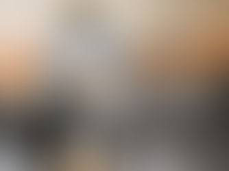 Person in cozy sweater reads a book on a bed with fairy lights, holding a mug of marshmallows. Relaxed, warm ambiance.