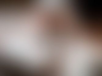 Woman with red nails pets a sleepy white cat lying on an open book, creating a calm and cozy atmosphere on a bed.