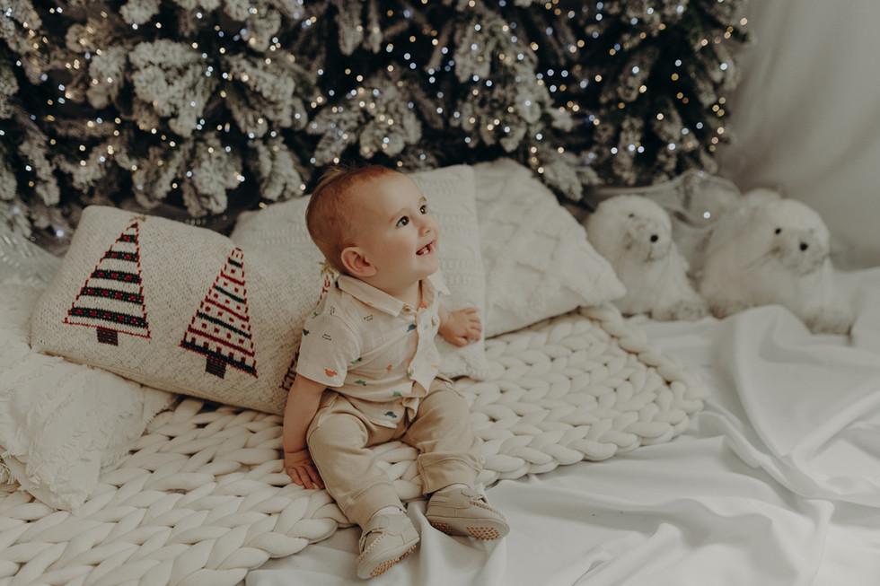 Bebê sorrindo no ensaio de Natal Vila Nevada com decoração clássica e tons clean.
