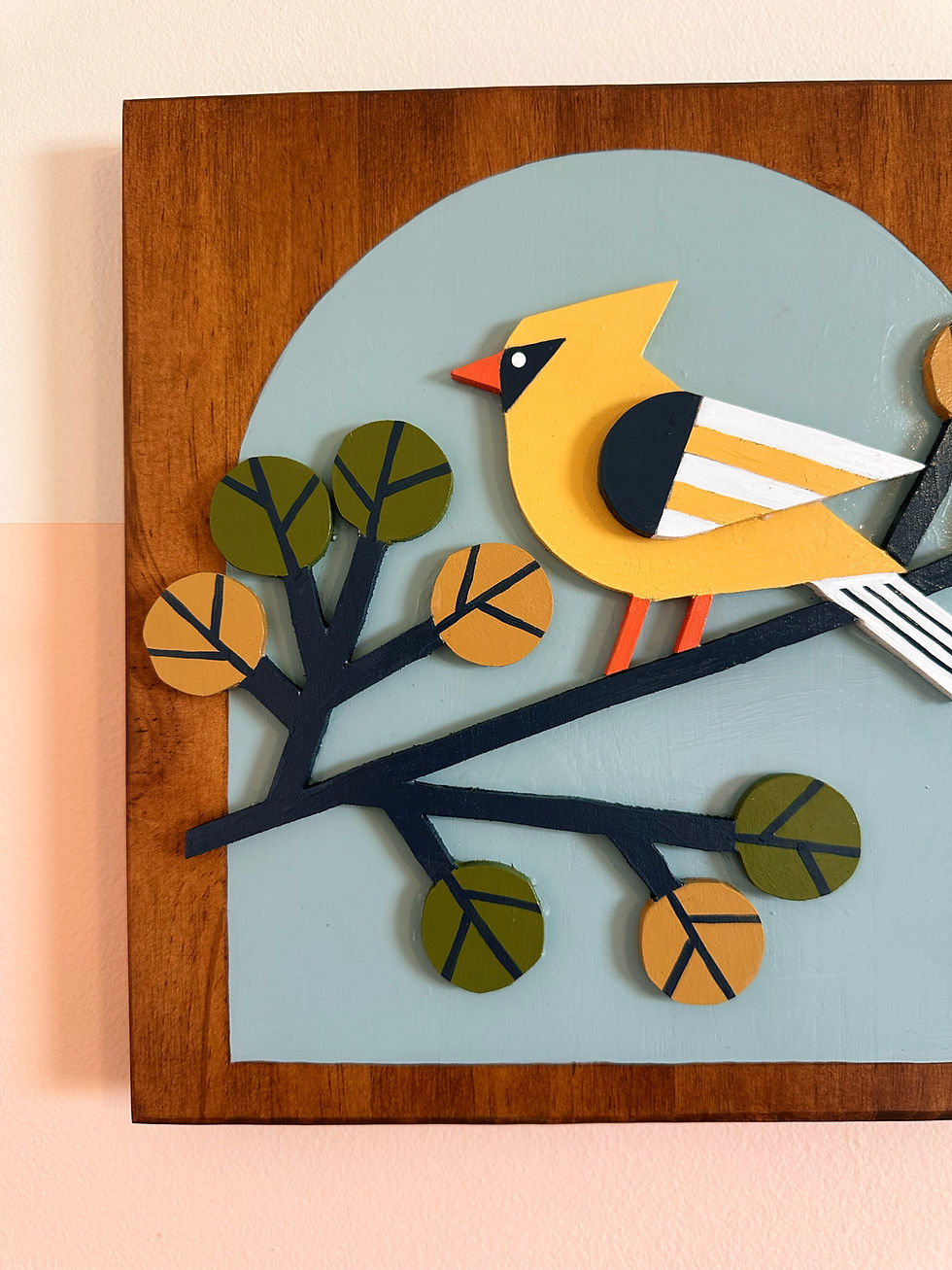 Stylized yellow bird paper art on branch with light blue background.