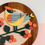 Thumbnail: Stylized colorful bird on a branch with orange berries, wooden frame.