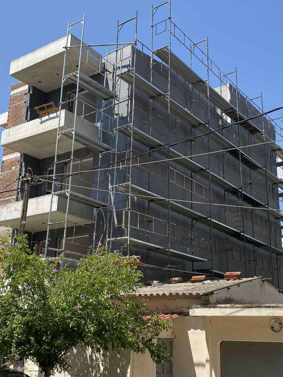 Building under construction with scaffolding and blue sky.
