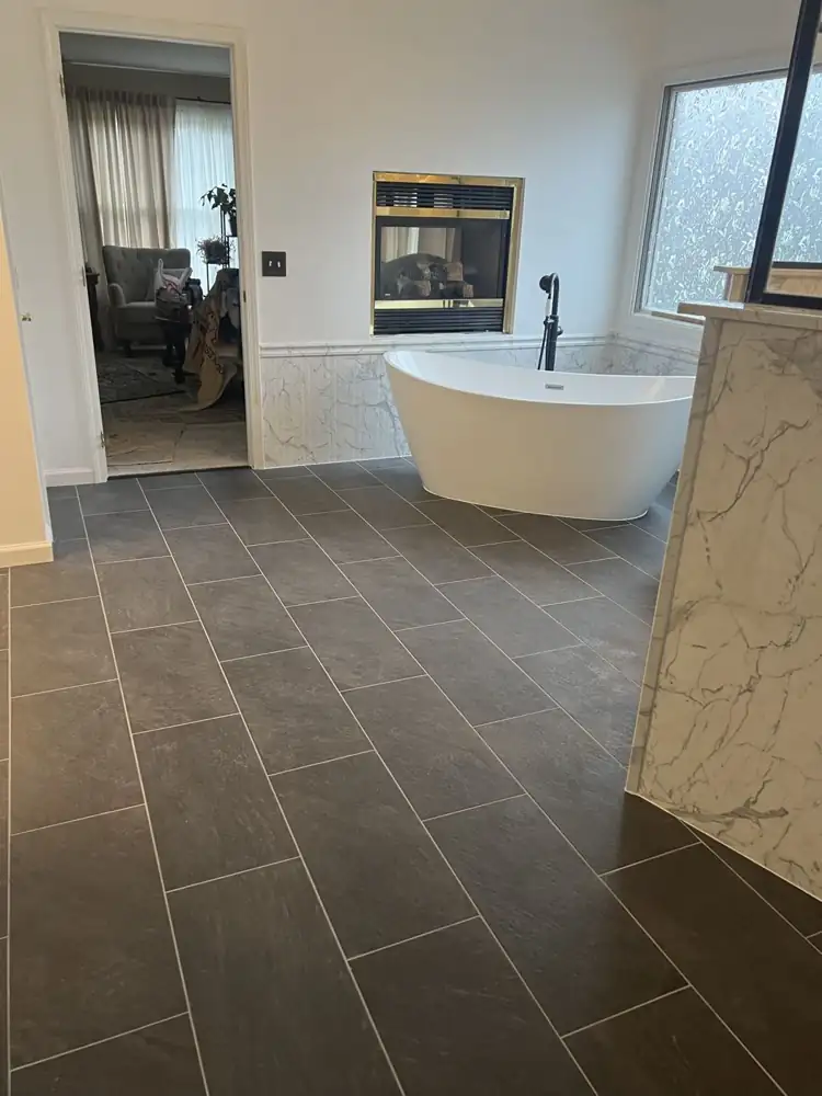 Primary bathroom with freestanding tub beside a gas fireplace and charcoal slate-look floor, Solon