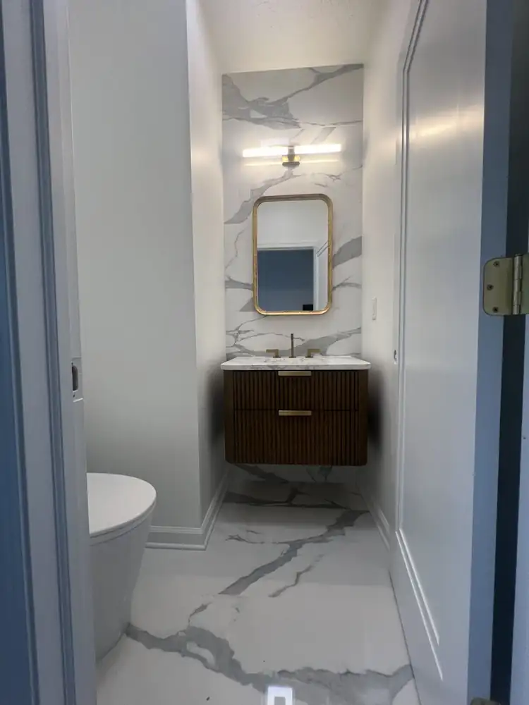 Powder room with marble-look porcelain wall and floor, fluted walnut vanity and brass fixtures, Hudson