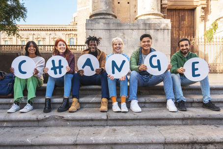 College students holding signs that spell “CHANGE,” representing Adlerian Psychology’s focus on growth, purpose, and creating change rather than staying stuck in past experiences