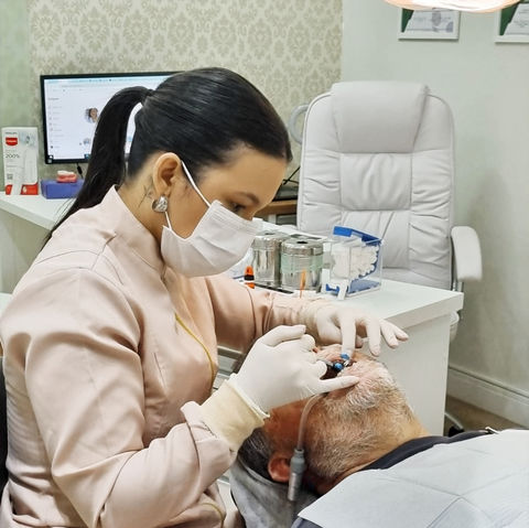 Dra. Larissa Brunca realizando limpeza dental com equipamento de ultrassom para remover tártaro e sujeira profunda.