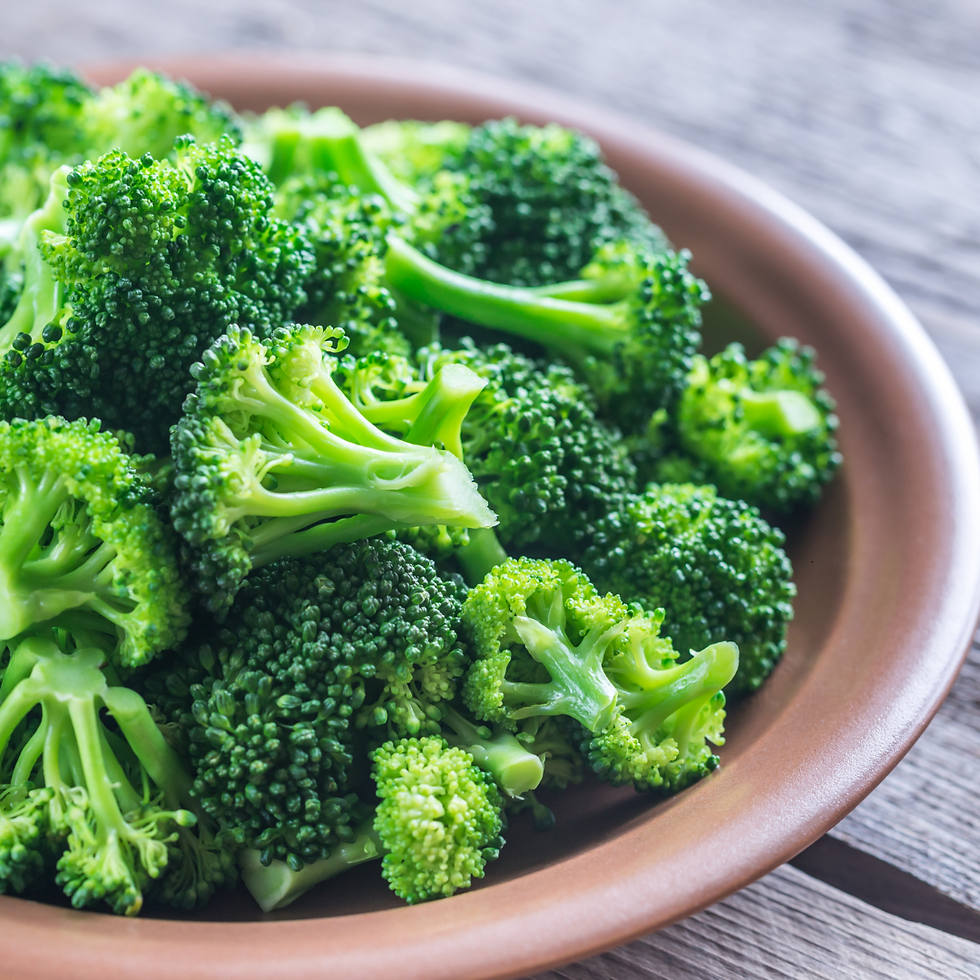 Fresh broccoli florets in a brown bowl on a rustic wooden table, showcasing vibrant green colors. No text visible.