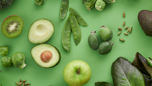 green background with fiberous foods including avocados, kiwi, brussels sprouts, nuts, seeds, spniach
