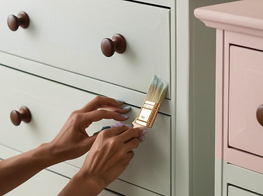 un zoom sur les mains d'une seule personne qui peint une commode de style scandinave avec