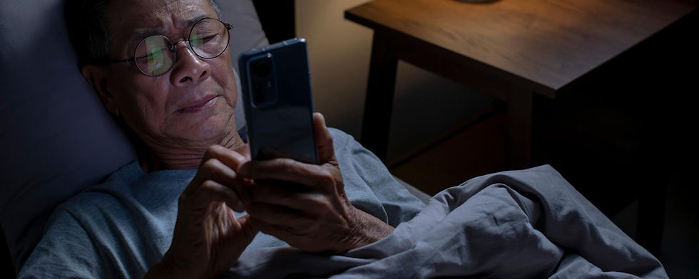 Older Man Looking at His Phone at night while in bed