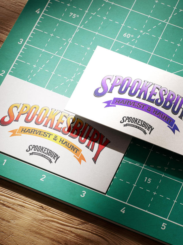 Two business cards on a cutting board with Spookesbury: Harvest & Haunt brand design printed on the cards.