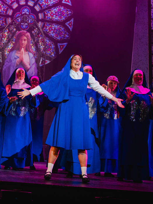 A cast member of Sister Act Musical performing a musical number on the Theatre Royal Portsmouth stage.