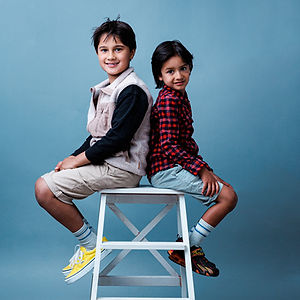 Two boys sit back-to-back on a stool, Kids Photoshoot