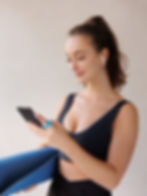 Woman checking phone, yoga mat, earbuds
